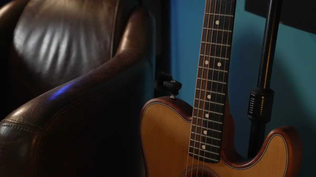 Détail : fauteuil en cuir et guitare posée contre le mur